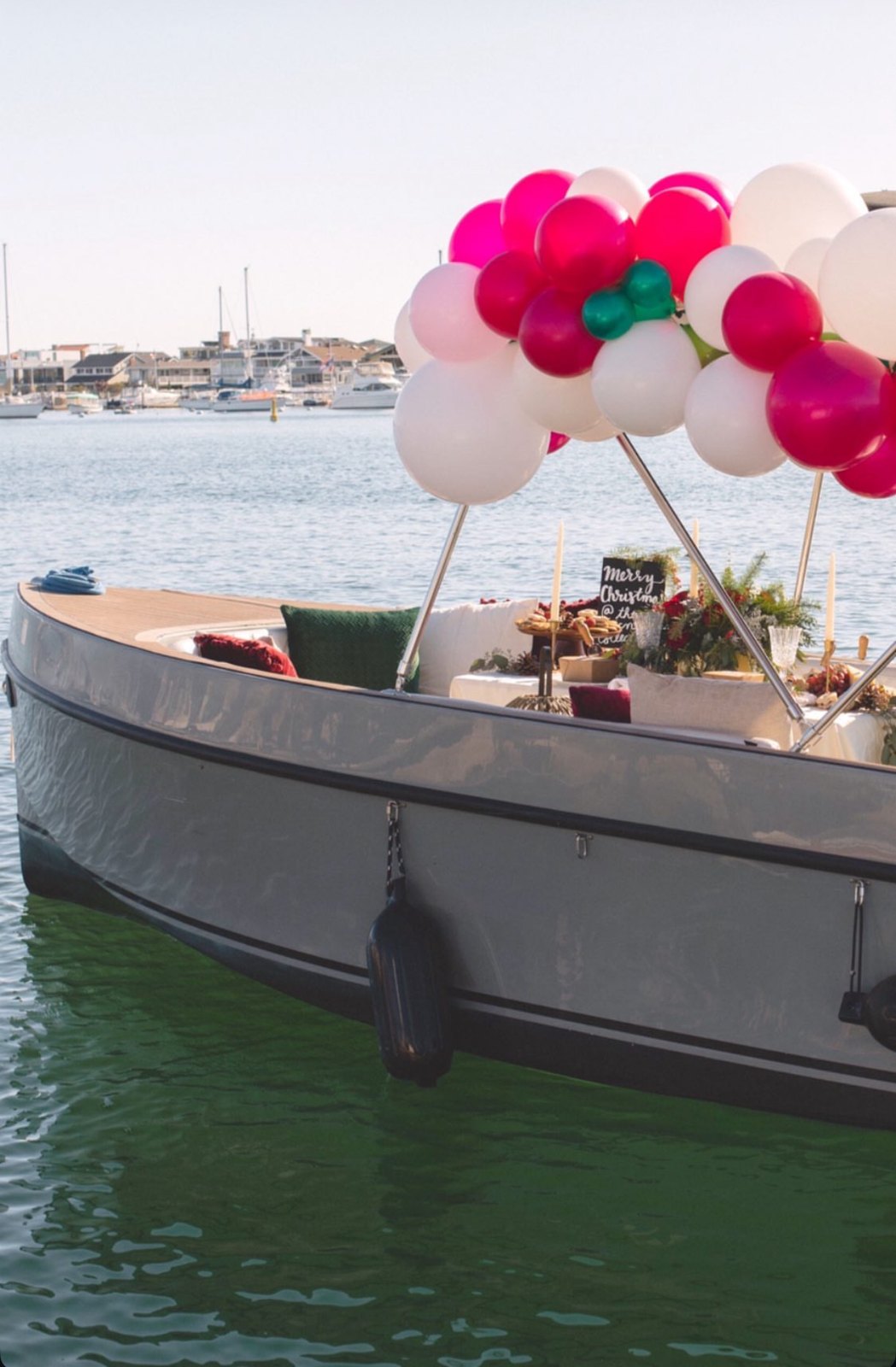 Holiday picnic on a harbor boat under a red, pink and white balloon garland