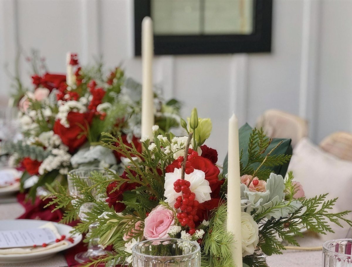 Red and white holiday tablescape with roses, evergreen and taper candles
